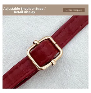 Detail of adjustable red leather shoulder strap with a polished gold square metal buckle
