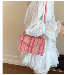 Detail view of pink striped woven crossbody bag paired with a vintage white lace dress