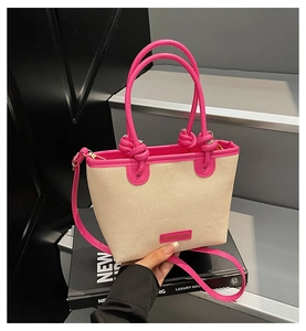 Detail der Sommer Stroh-Beuteltasche mit rosa Ledergriffen und Markenanhänger
