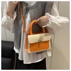 Detail of color-block tote bag with orange leather, woven texture, and gold buckle