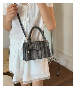 Detailed close-up of a woven texture shoulder bag with flap cover and top handle