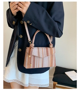 Detail of colorful striped straw crossbody bag with golden hardware and round handle