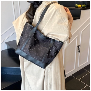 Détail du grand sac cabas noir avec motifs papillons sur un mannequin en manteau