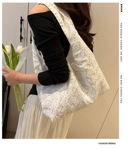 Close-up of white tote bag featuring yellow floral embroidery and lace hollow details