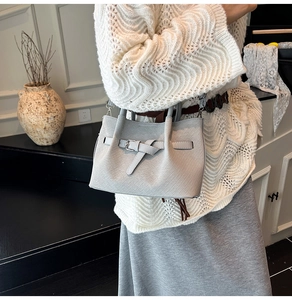 Detail of light blue pleated bucket bag with woven texture and buckle decoration