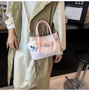Pink pleated bucket bag with long strap and cute white plush monster keychain charm