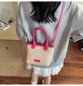 Detail der Strohstrandtasche mit rosa Lederbesatz und Umhängeriemen an einem Model