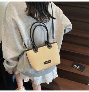 Detail einer handgewebten Stroh-Strandtasche mit schwarzen Ledergriffen auf einer Holztreppe