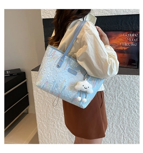 Detail of light blue tote bag featuring rainbow wave embroidery and cloud pendant