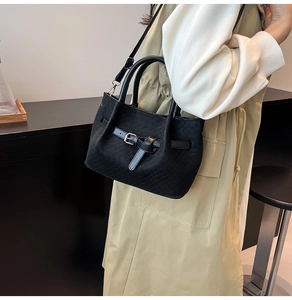 Detail of black woven bucket bag with silver buckles and adjustable shoulder strap