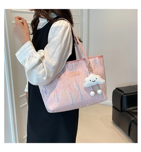 Pink striped tote bag with wave embroidery and cloud charm detail shown in a room