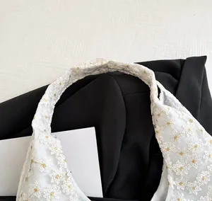 Detailopname van de witte kanten handvatten van een canvas tote tas met borduurwerk