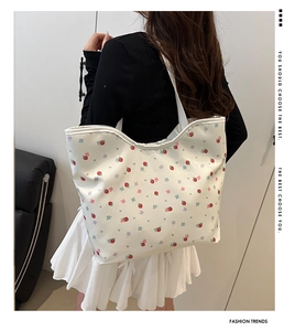 Close-up of large tote bag with strawberry and floral prints worn on a shoulder