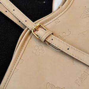 Détail d'un cabas beige avec gaufrage floral et boucle en métal doré élégante
