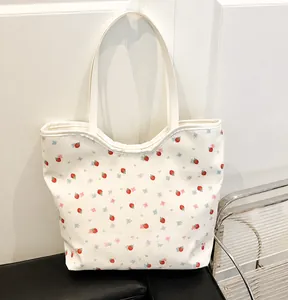 Detail showing red strawberry and blue floral prints on a white canvas tote bag surface
