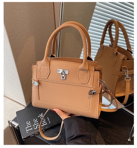 Detail of tan pebble leather textured handbag featuring silver square lock and strap