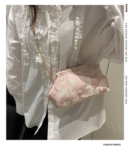 Close-up of pink silk cloud bag with white floral embroidery and gold chain strap