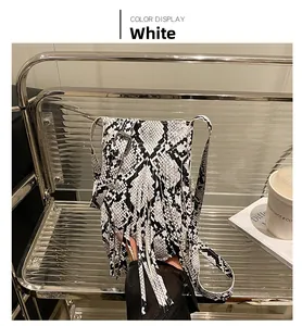 Détail du sac à main blanc à motif serpent avec de longues franges sur une chaise