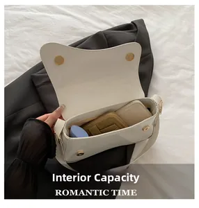Detailed view of the white patent leather shoulder bag interior with mobile and cosmetics