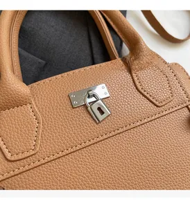 Close-up of silver metal buckle and lock on brown lychee texture leather handbag