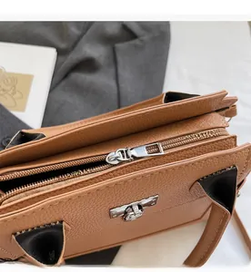 Detail of brown litchi grain leather handbag with smooth silver zipper and sturdy handle