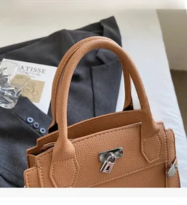 Detailed macro of tan lychee grain leather handbag with silver metallic turn-lock closure