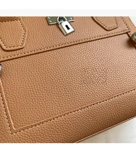 Close-up of brown litchi pattern leather with white stitching and silver metal lock detail