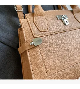 Close-up of camel litchi texture leather with silver metal lock on handbag