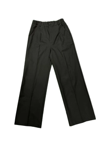 Detail view of high-waisted black trousers with sharp front creases and side pockets