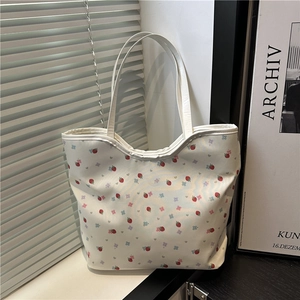 Floral shoulder bag with strawberry prints and drawstring closure in a bright indoor setting