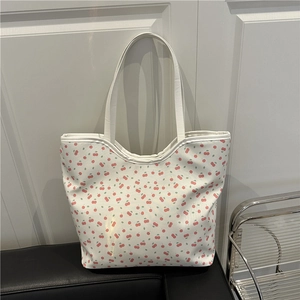 Fresh white tote bag with red cherry prints and matching shoulder straps in a home setting