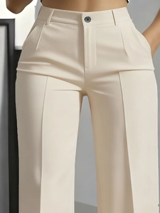 Detail of high-waist beige suit trousers featuring a pleated waist and single button closure