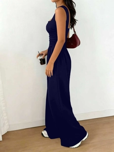 Side view of dark blue sleeveless wide leg jumpsuit with waist pleats and square neckline