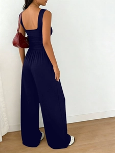 Detail view of the sleek waist pleats and fabric texture of navy wide-leg jumpsuit