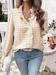 Detail of ruffle trim on the collar and cuffs of a yellow gingham long sleeve shirt