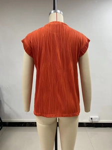 Detail of orange textured short sleeve top showing ripple pleat fabric on a mannequin