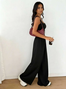 Detail of solid black sleeveless top and wide-leg trousers set in soft indoor light