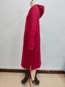 Side view detail of a long red oversized hoodie with side slits and front pocket