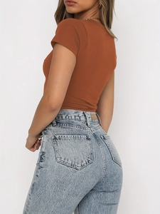 Gros plan sur un crop top orange caramel et un jean taille haute délavé à la neige