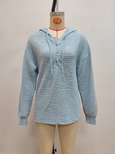 Detailed view of light blue hoodie featuring horizontal pleated texture and three-button placket