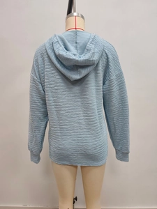 Detail of light blue hoodie featuring unique horizontal wave textured pleated fabric