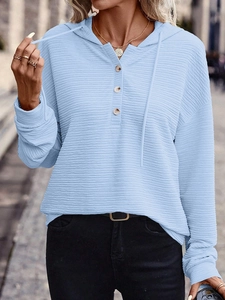 Detail of light blue hooded jacket featuring unique horizontal pleated texture and buttons