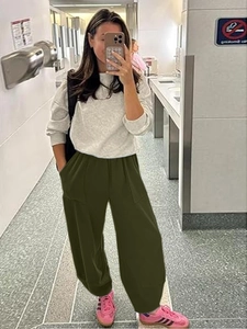 Detail view of dark green high-waisted sweatpants with cuffed hem and cotton fabric texture