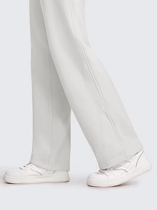 Detailed view of grey wide-leg trousers draped over white sneakers in a minimal style