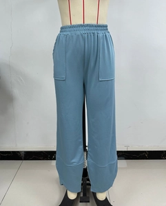 Detail of light blue wide-leg trousers featuring elastic high waist and side split hem
