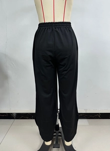 Detail of black wide-leg trousers featuring elastic waistband and soft draping fabric