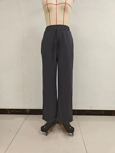 Detail of grey wide-leg joggers showing the elastic waistband and woven drawstring