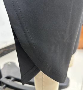 Detail of the cross-slit hem with precision double stitching on black knitted pants