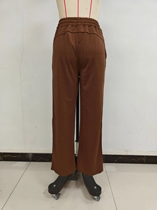 Detail of deep brown wide-leg sweatpants with elastic drawstring waist on a mannequin