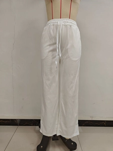 Detail of white wide-leg sweatpants showing elastic high waist and adjustable drawstring